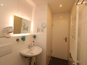 A bathroom with a white sink, a mirror, a hairdryer, and a towel rack.