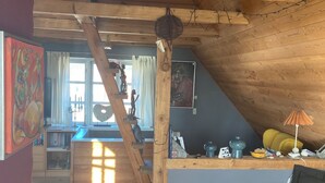 Et rustikt træinteriør med en køjeseng, en sofa, et spisebord og et lille køkken.