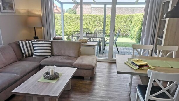 A modern living room with a sectional sofa, a coffee table, and a dining area with a table and chairs. - Dinkla 1 Comfortable Holiday Residence (Dornum)