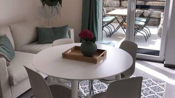 A modern living room with a round white table, grey chairs, a beige sofa, and a patterned rug.