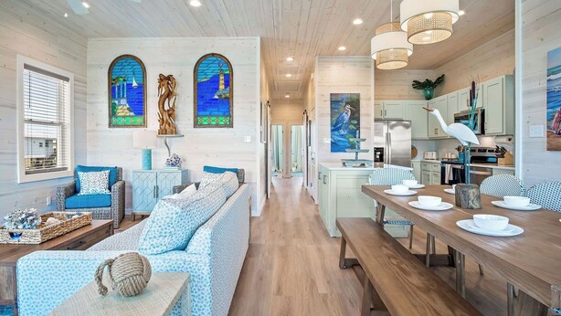 A spacious living area with a long wooden dining table, a sofa, and a kitchen in the background. - Private Pool|Steps to Beach|Ocean View (Port Aransas)