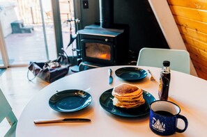 A table with plates of pancakes, a coffee mug, and a bottle of soda.