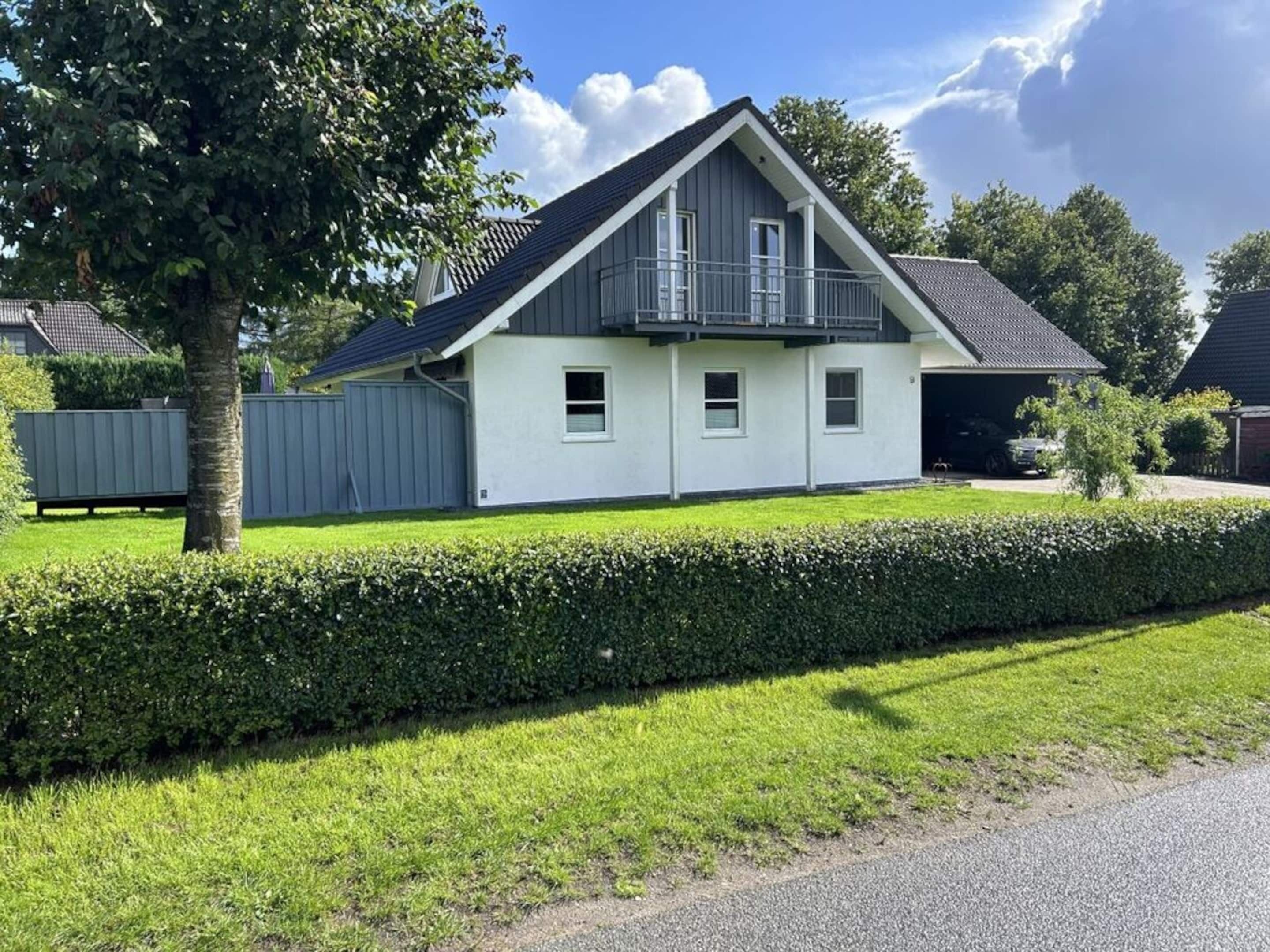 Ett tvåvåningshus med en balkong, ett garage och en välskött gräsmatta.