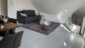 A modern living room with a dark sofa, a round coffee table, and a television.