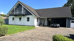 A two-story house with a garage, a balcony, and a paved driveway.