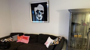 A modern living room with a sectional sofa, a glass coffee table, and a cabinet with glass doors. - Pink Cow Modern Retreat (Groemitz)