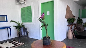 A room with a round wooden table, a potted plant, a blue chair, and a green door. - Pousada Villa Mar Porto (Ipojuca)