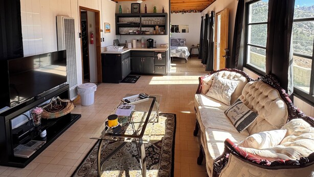 A spacious living area with a wooden ceiling, a sofa, a TV, and a kitchen in the background. - Alarcon Ranch  (Weldon)