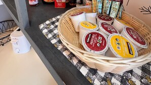 A kitchen counter with various condiments, including a bottle of hot sauce, a jar of peanut butter, and a basket of yogurt cups. - Alarcon Ranch  (Weldon)
