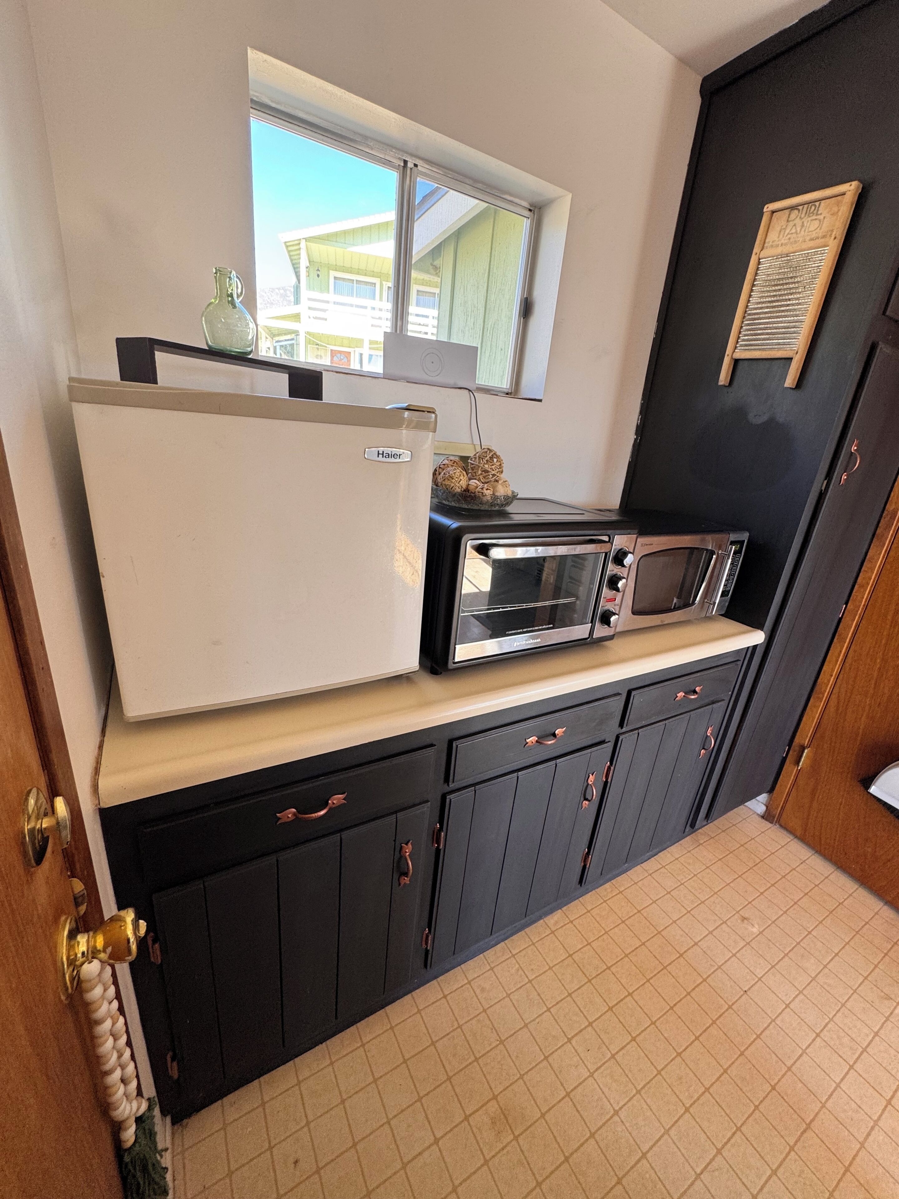 A compact kitchen with a refrigerator, toaster, and microwave on a countertop.