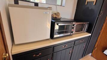 A compact kitchen with a refrigerator, toaster, and microwave on a countertop.