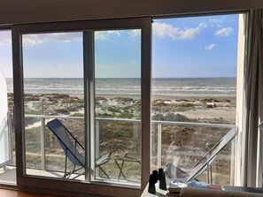 A room with large windows overlooking a beach. There are two chairs and a table with a telescope and binoculars. - Noordpas Comfortable Holiday Residence (Koksijde)