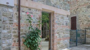 A stone building with a doorway, a potted plant, and a metal gate. - Apartment in Casola Near Torre di Casola (Casola in Lunigiana)