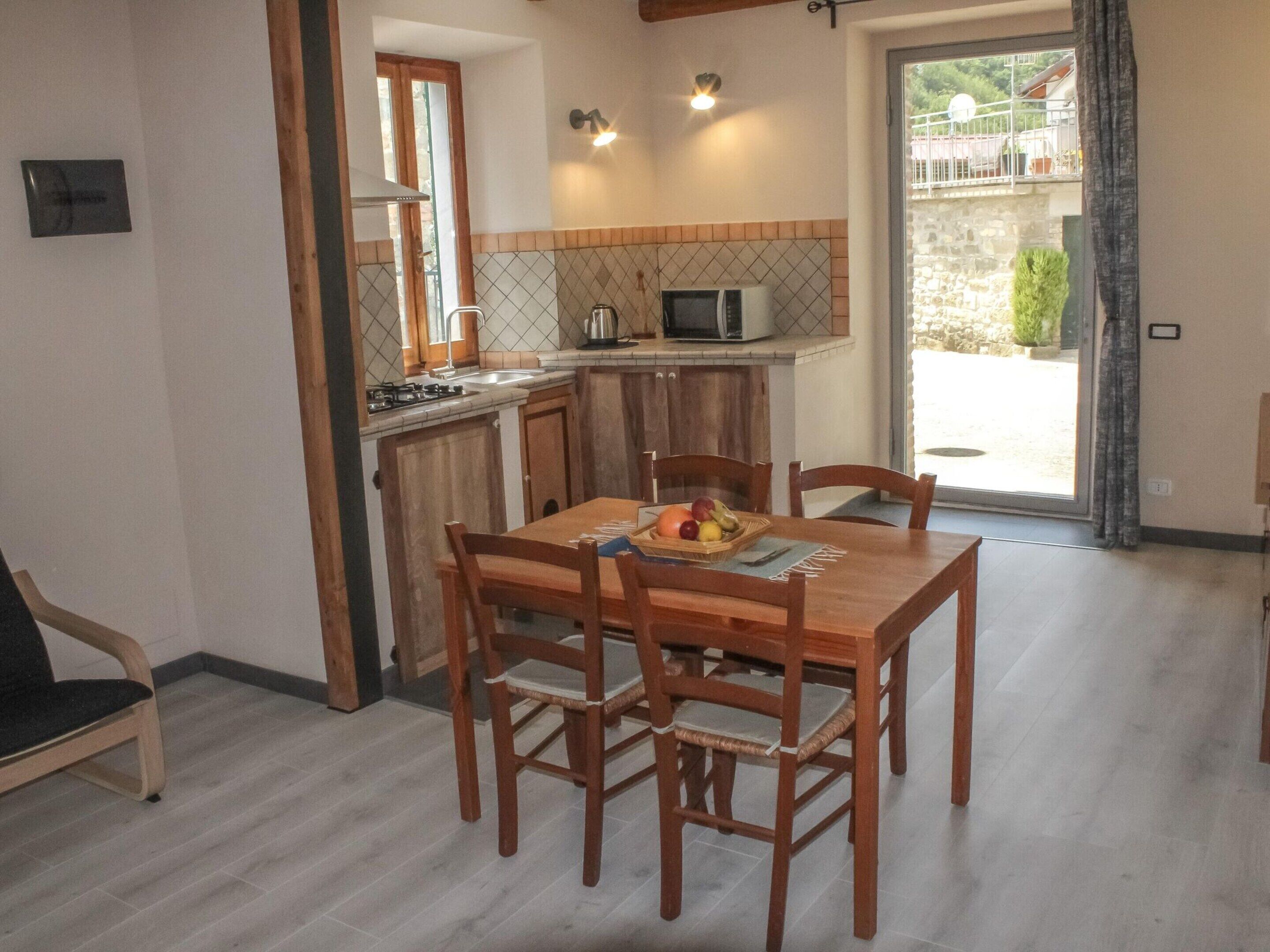 Una cocina compacta con armarios de madera, una mesa de comedor con sillas y una ventana pequeña.