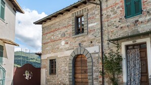 A stone building with a wooden door and a gate. - Apartment in Casola Near Torre di Casola (Casola in Lunigiana)