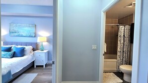 A bedroom with a bed, nightstand, and lamp, and a bathroom with a shower and toilet. - Comfy Condo near Promenade Mall (Vaughan)