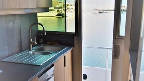 A compact kitchen with a sink, a window, and a view of a marina. - Exclusive Yacht With a Roof Terrace (La Rochelle)