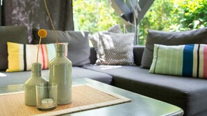 Ein modernes Wohnzimmer mit einer Couch, Kissen und einem Tisch mit dekorativen Flaschen und einer Kerze.