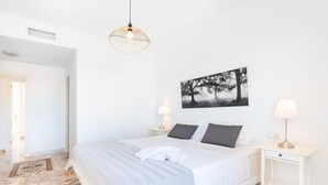 Une chambre d’hôtel avec un grand lit, deux lampes de chevet, un tableau accroché au mur et un sol en marbre.