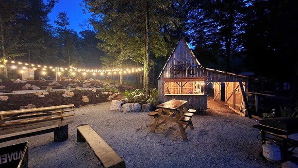 A rustic outdoor setting with a wooden structure, picnic tables, and string lights. - Base Camp | Lookout Lodge #2 (Big Prairie Township)