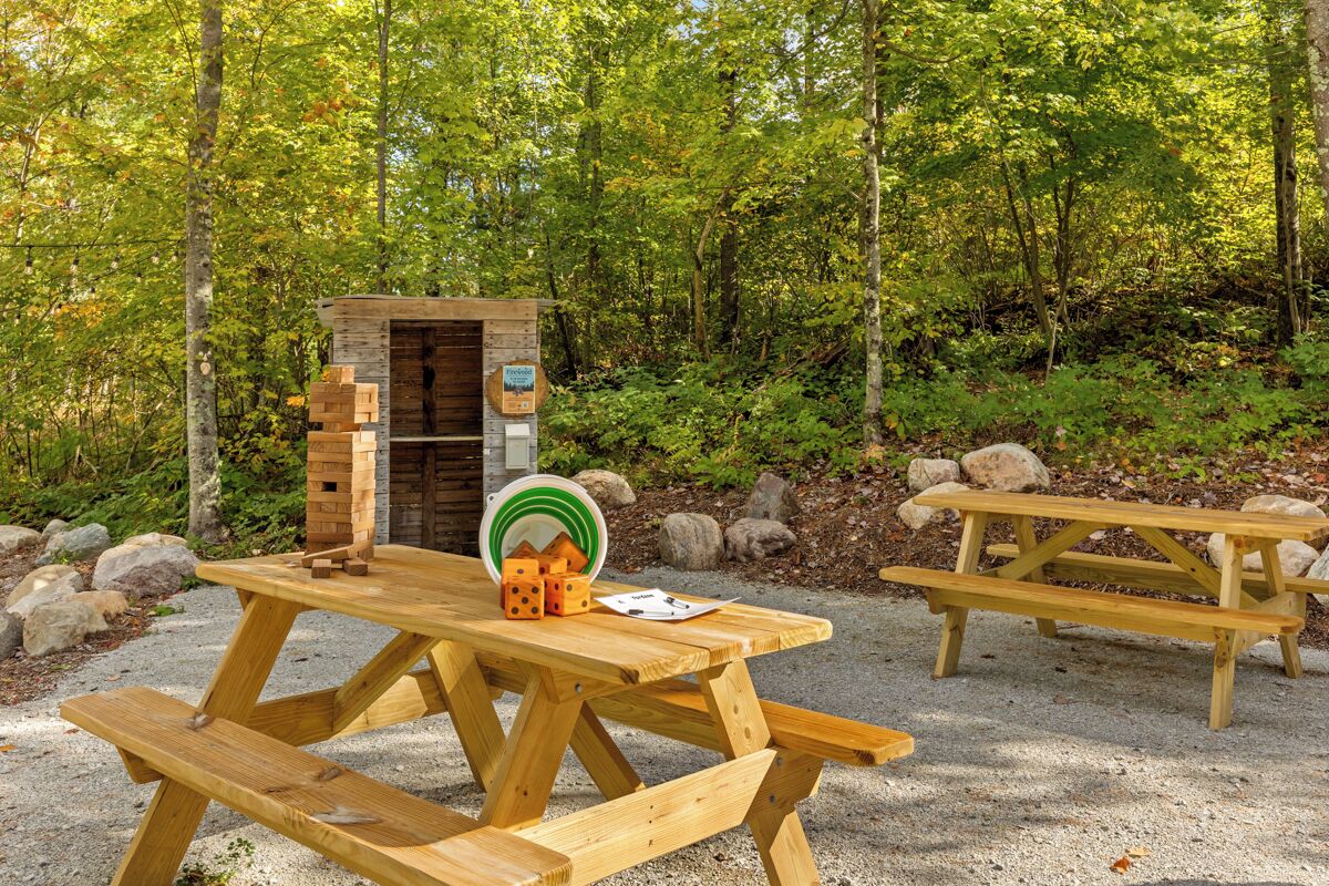 A picnic area with wooden benches and a small brick structure, surrounded by trees.