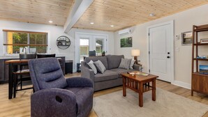 A modern living room with a grey sofa, a purple armchair, a wooden coffee table, and a bookshelf. - Base Camp | Lookout Lodge #2 (Big Prairie Township)