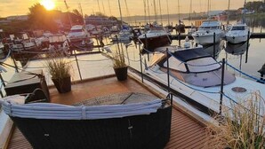 Una marina con barcos amarrados, un área de descanso cubierta con plantas y una terraza de madera.