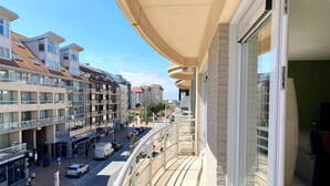 A balcony with a view of a city street, buildings, and a clear sky. - Apartment in Nieuwpoort With Ocean Views (Nieuwpoort)