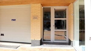 A building entrance with a garage door, a sign indicating a parking area, and a glass door leading into the building. - Apartment in Nieuwpoort With Ocean Views (Nieuwpoort)