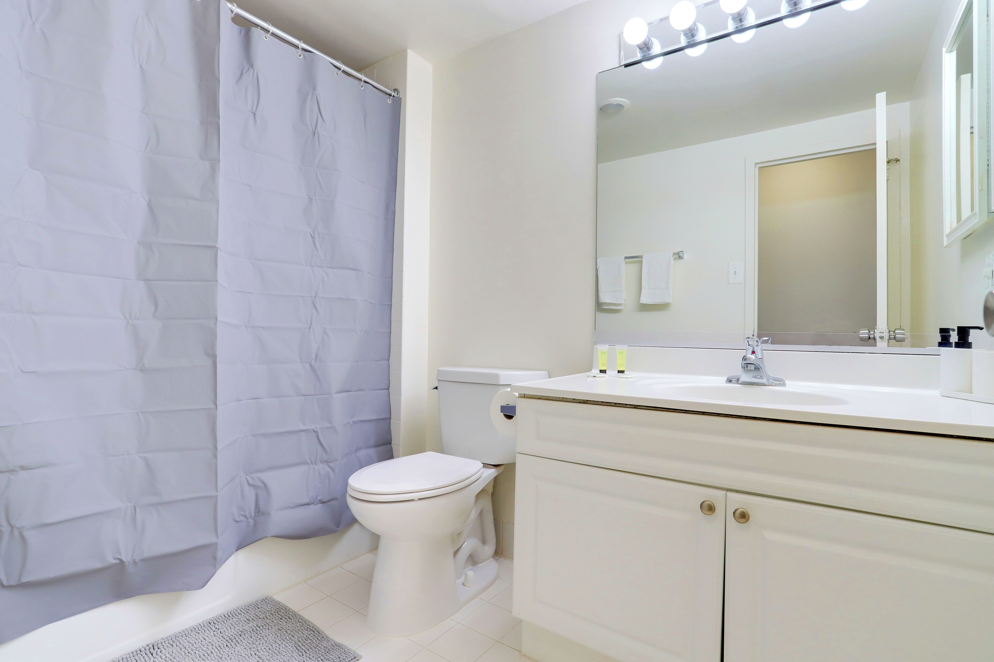 A bathroom with a white toilet, a sink with a mirror, and a shower curtain.