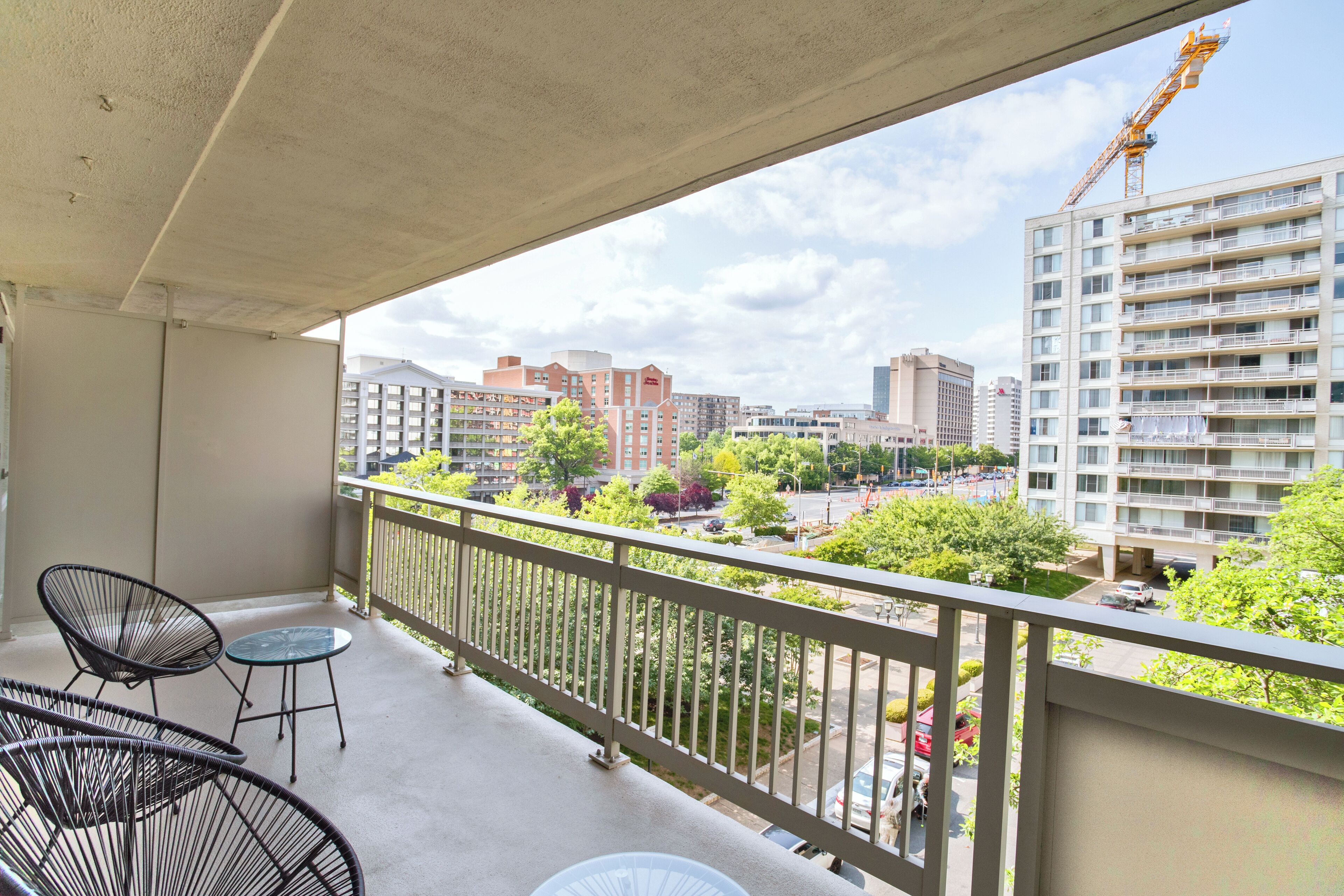A balcony with a view of a cityscape, including buildings and a construction crane.