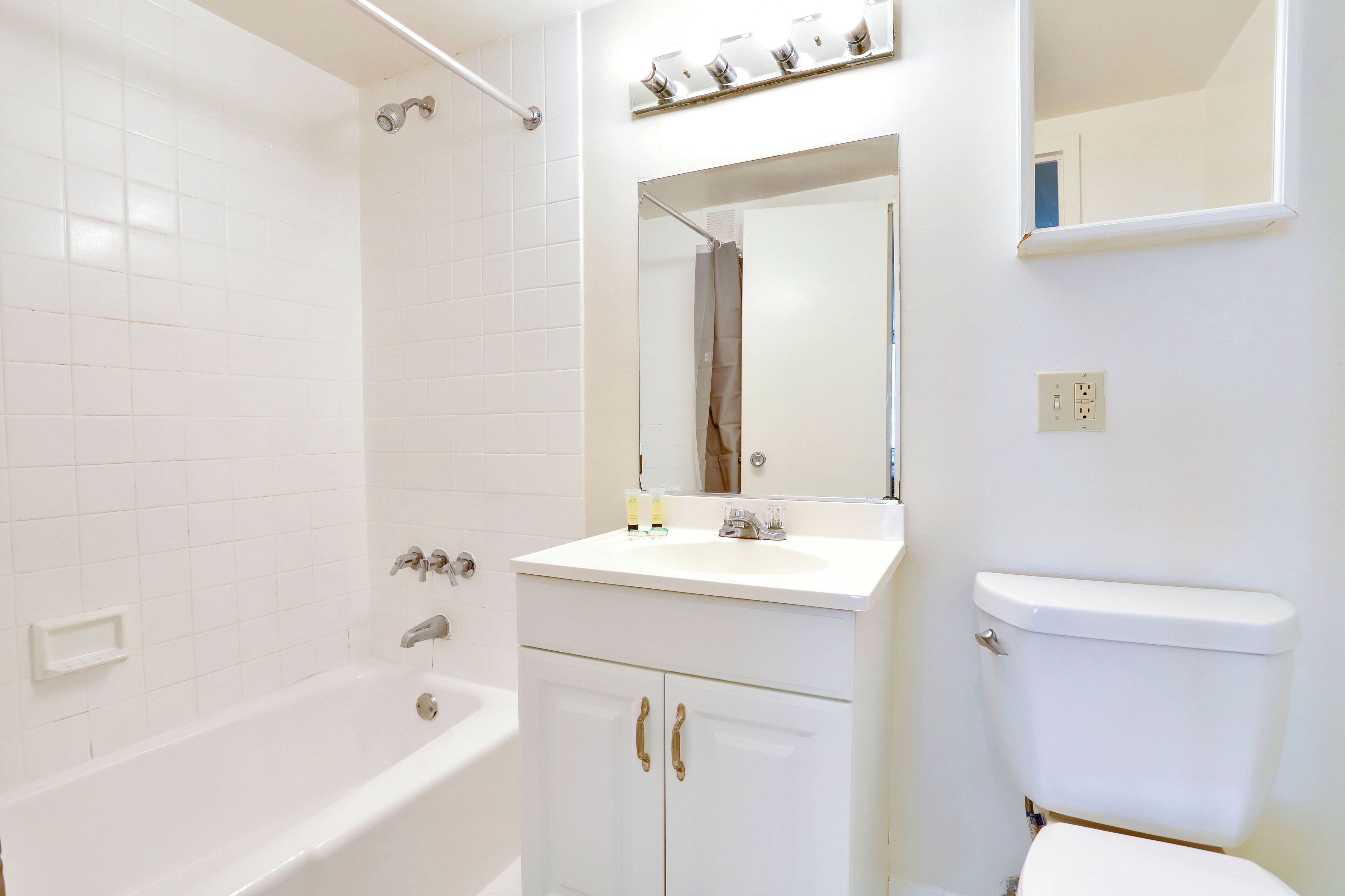 Une salle de bain avec une baignoire blanche, un lavabo avec un miroir au-dessus, et des toilettes.