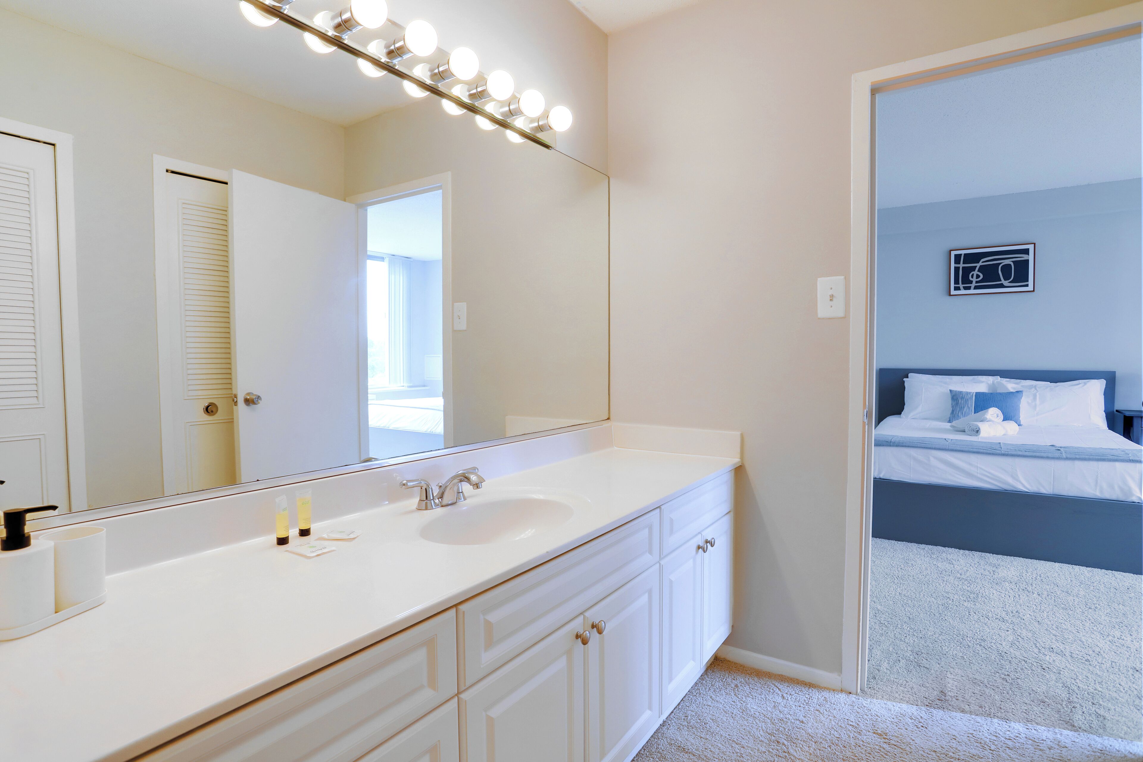 A bathroom with a large mirror, a sink, and a vanity with drawers.