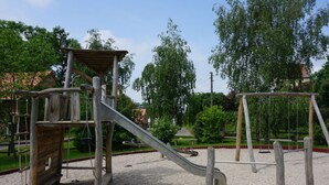 Une aire de jeux avec un toboggan, des structures d’escalade et des balançoires.