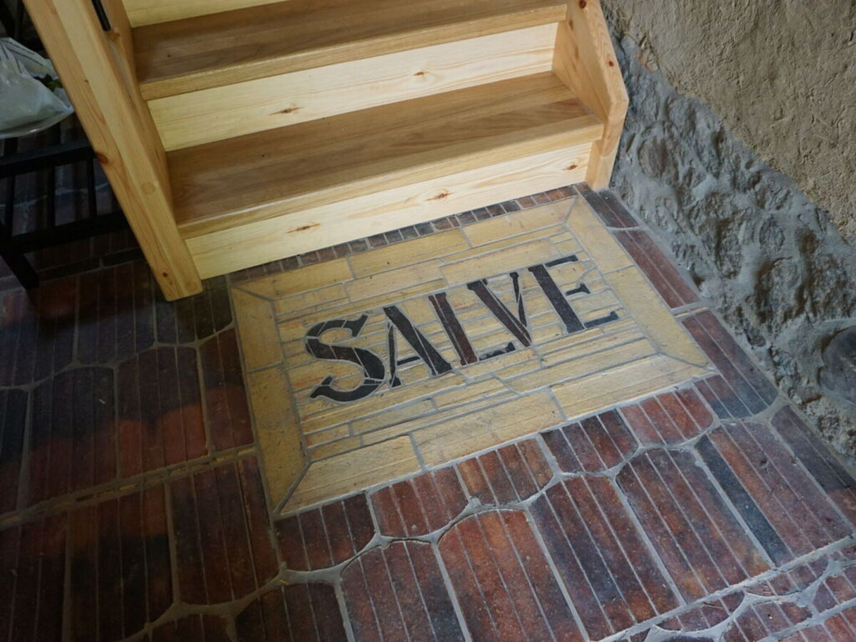 Un banco de madera con un cartel que dice 'SALVE' sobre un suelo de ladrillo.