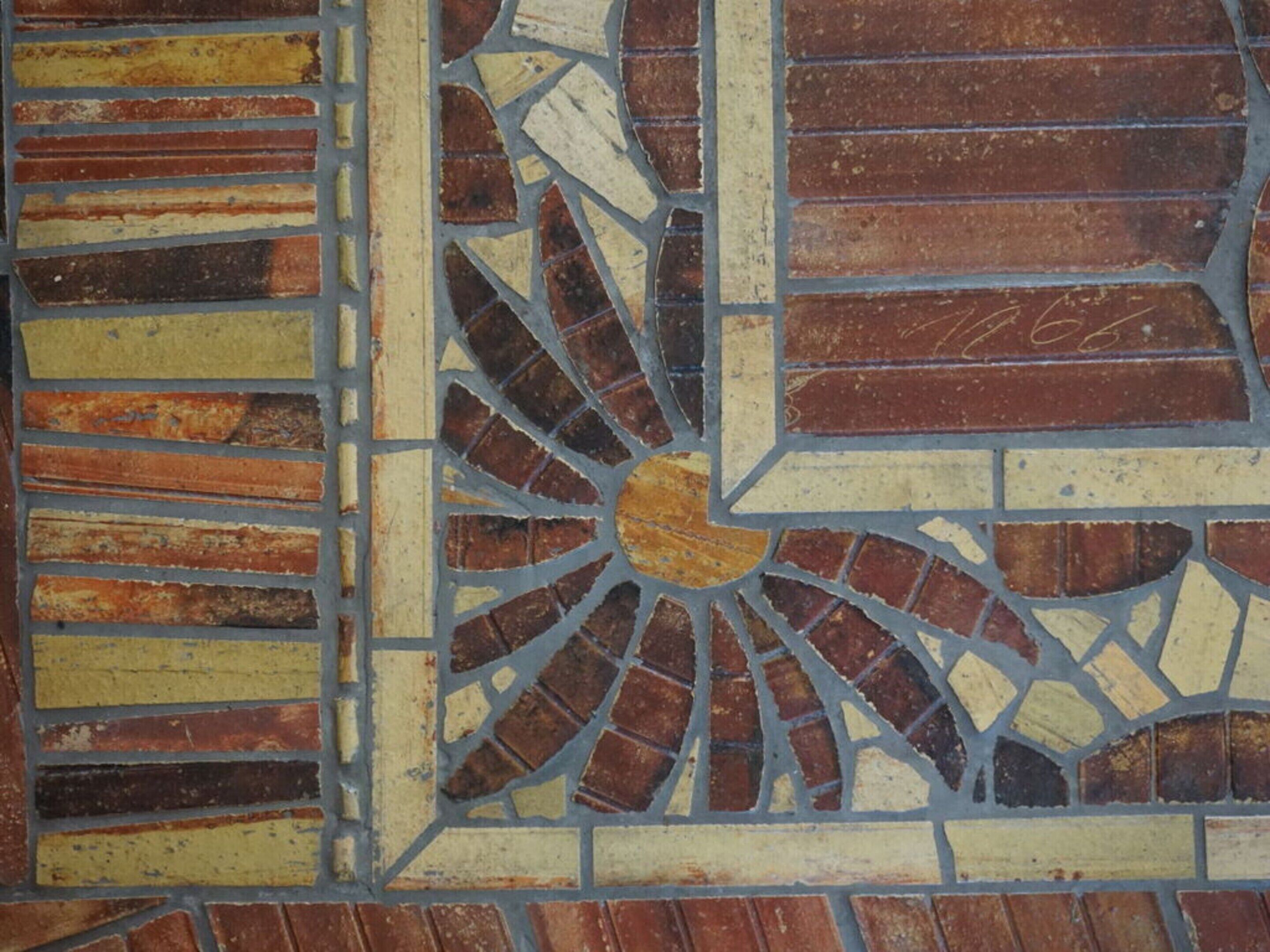 A mosaic tile pattern with a central circular design and rectangular borders.
