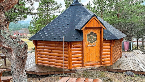 A small wooden cabin with a hexagonal door and a sloped roof, surrounded by trees and a picnic table in the foreground. - 4 Person Holiday Home in Lysoysundet (Orland)