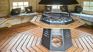 A cozy cabin interior with a central wood-burning stove, wooden benches, and a sloped ceiling. - 4 Person Holiday Home in Lysoysundet (Orland)