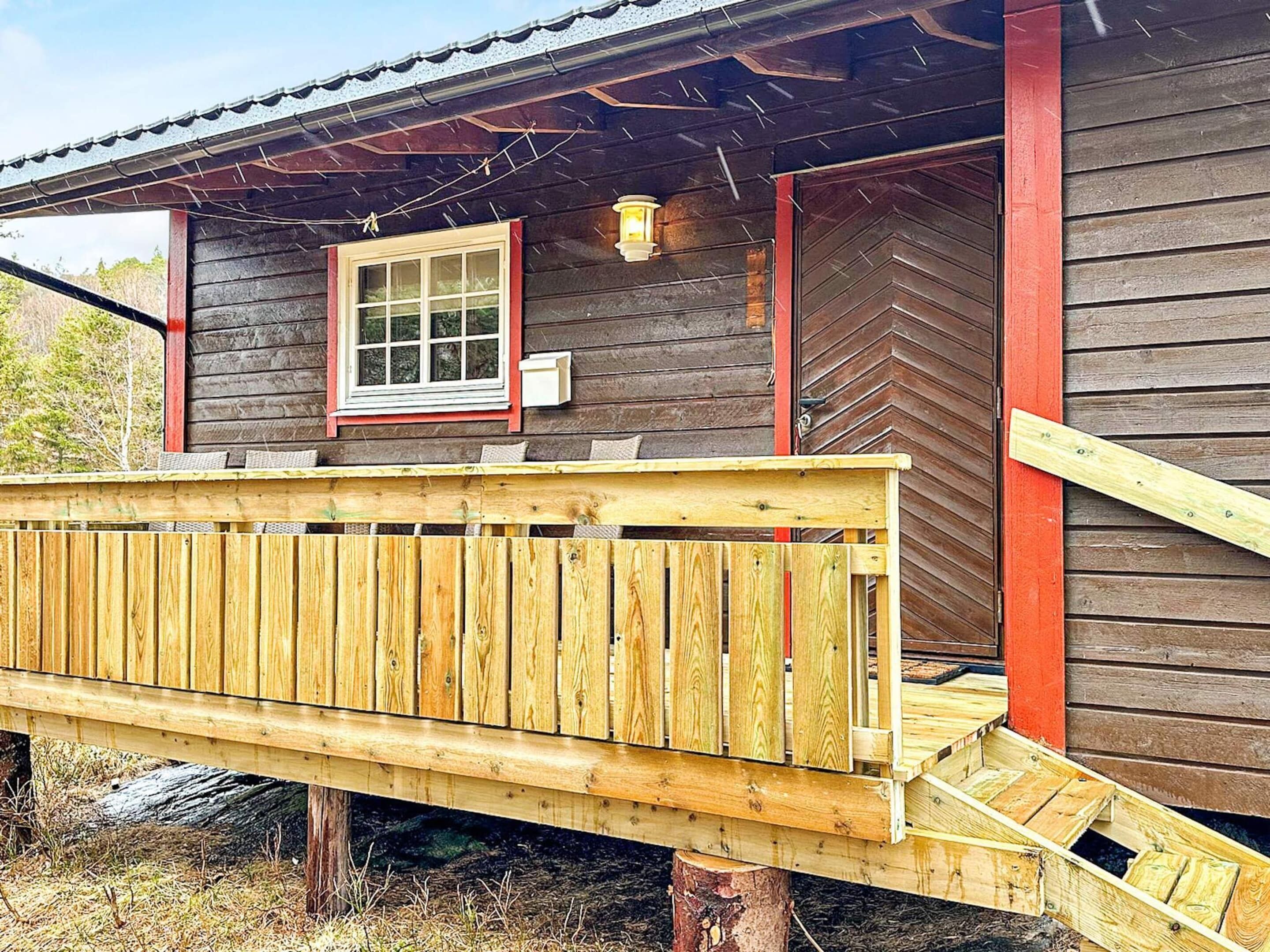 A wooden cabin with a wooden deck leading to a door.