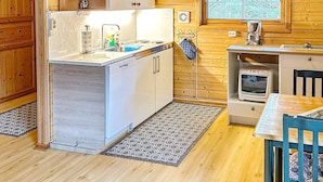 A compact kitchen with wooden walls, a built-in dishwasher, a stove, and a window with a view of trees. - 4 Person Holiday Home in Lysoysundet (Orland)