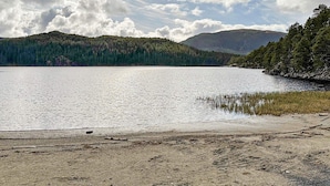 A lake with a sandy shore and dense forested hills in the background. - 4 Person Holiday Home in Lysoysundet (Orland)