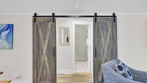 A room with a sliding barn door, a mirror, and a patterned sofa.