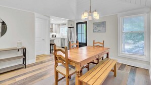A modern kitchen with white cabinets, a wooden dining table, and a bench.