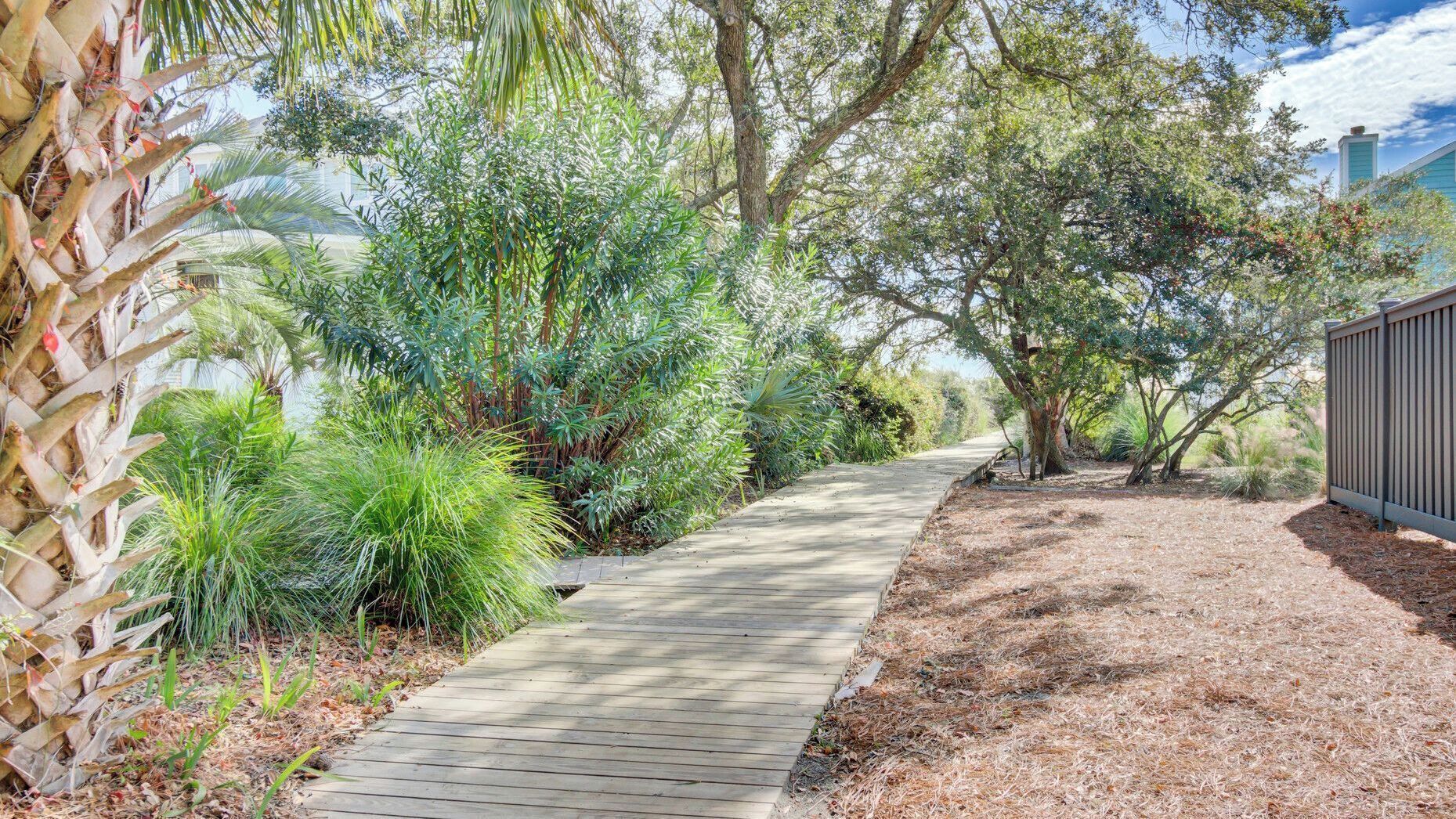 Un sentier en bois aménagé dans un jardin paysager, agrémenté de diverses plantes et arbres.
