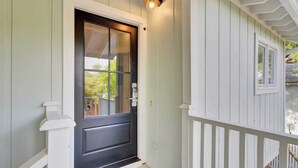 A front door with a glass panel, a mailbox, and a porch with a white railing.