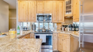 A modern kitchen with wooden cabinets, stainless steel appliances, granite countertops, and a view of the outdoors. - Sunvail by Avantstay 10min Walk to Ski Lifts! (Vail)