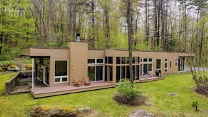 A modern cabin with a deck, large windows, and a forest backdrop. - Secluded + Modern Enclosed Patio, Forest Views Woodland Zen by Avantstay (Housatonic)