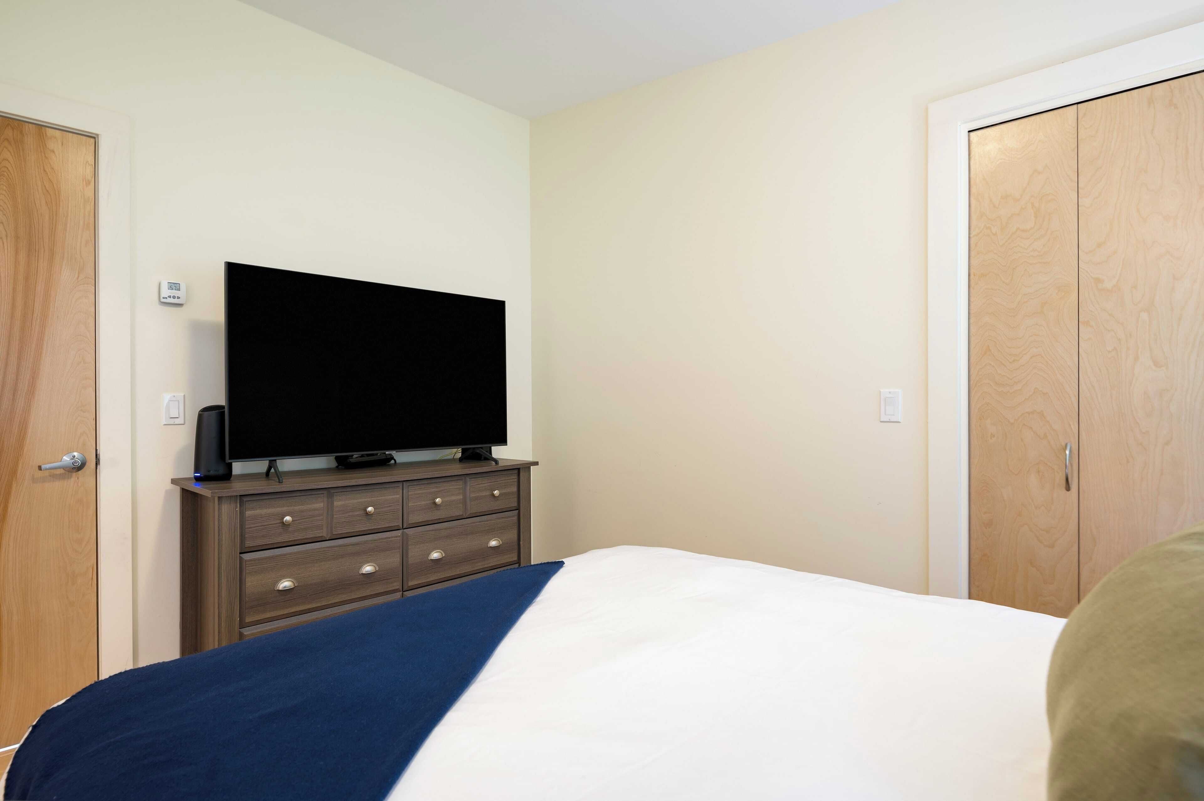 A hotel room with a bed, a dresser, a television, and a wardrobe.