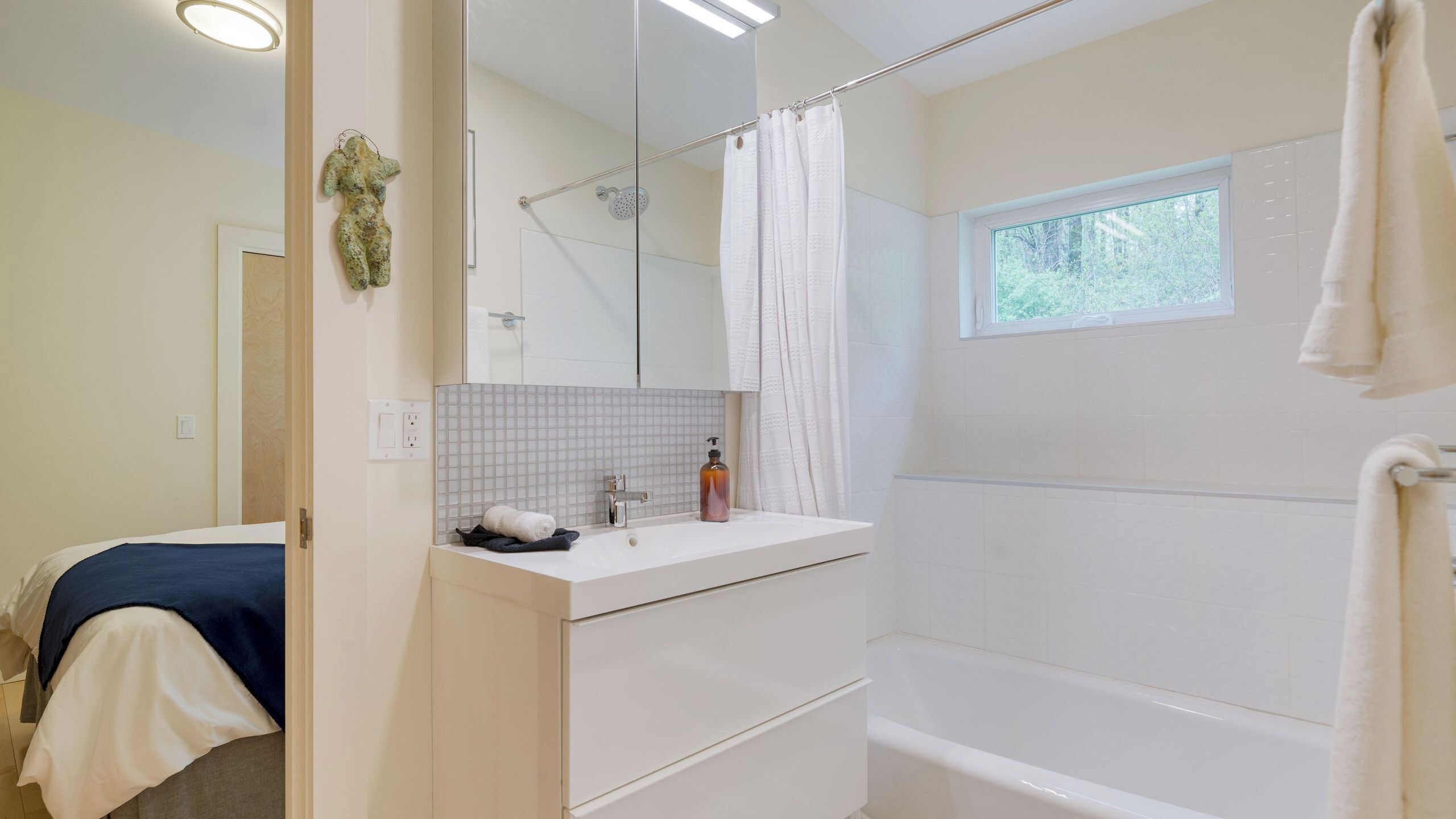 Un baño con bañera, ducha, lavamanos con espejo y ventana.