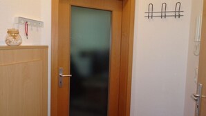 A wooden door with a frosted glass panel, a wall-mounted telephone, and a hook for keys. - 1 in House Weser 1 Comfortable Vacation Home (Cuxhaven)